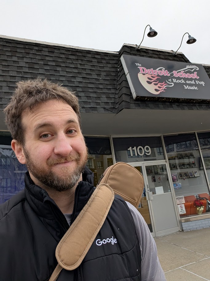 Alex holding a guitar and smiling